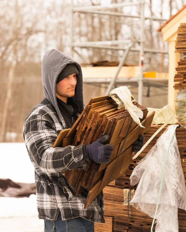 Elijah carrying a bundle of cedar shakes on a roofing job
